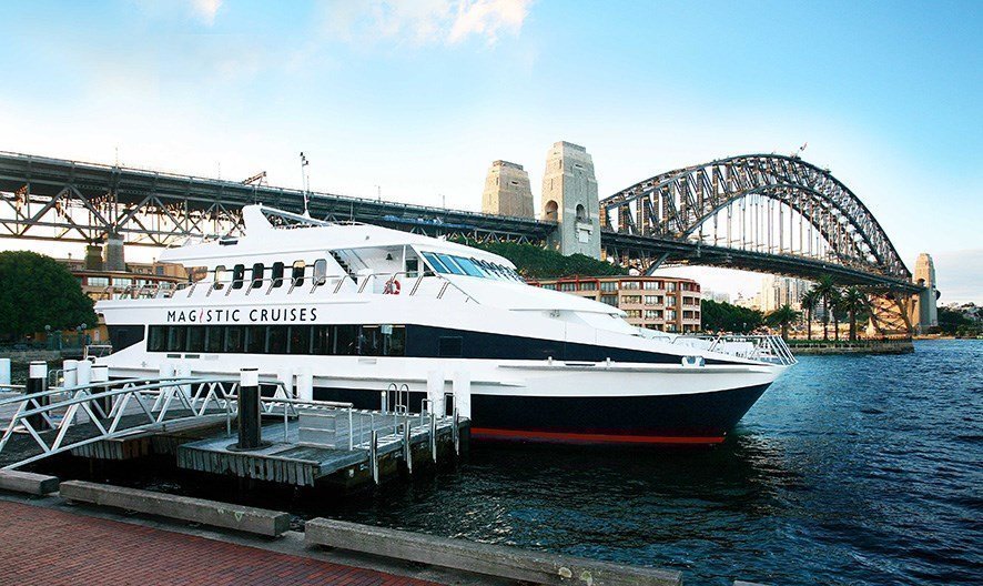 Popular catamaran with spacious decks sails under the Harbour Bridge, across the harbour waterfront